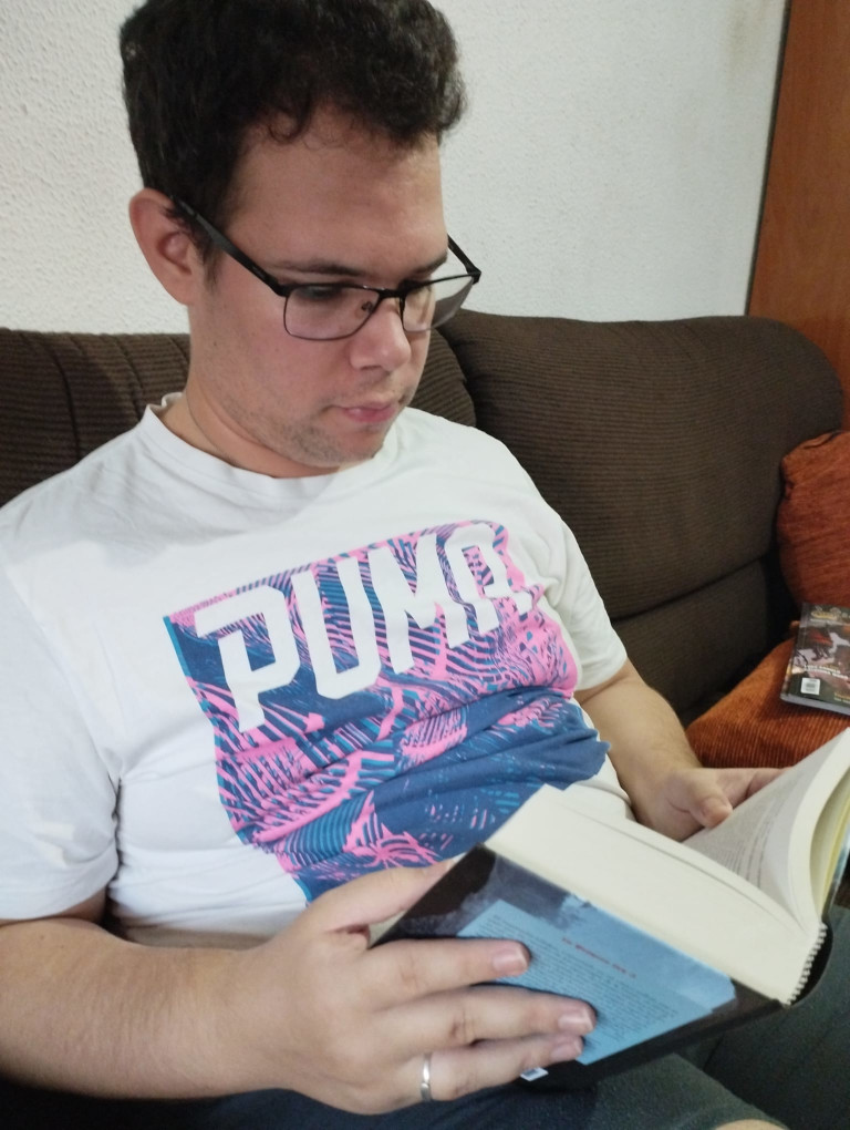 Fotografía de Antonio, sentado en un sofá con un libro
