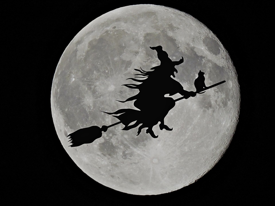 Una bruja vuela con su escoba frente a la luna llena